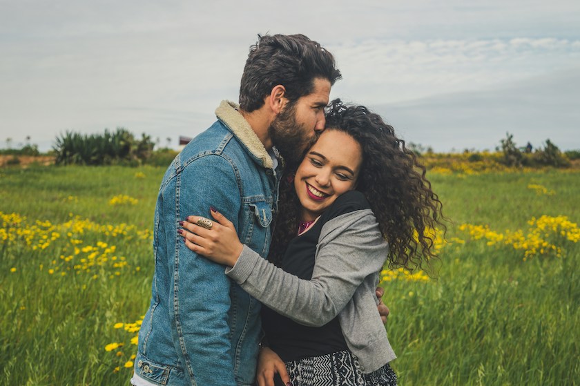 A husband kisses his wife on the head as they walk in the countryside reflecting on their future as a married couple.