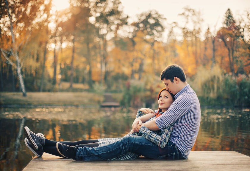 Couple sit on a deck next to a lake reflecting on their future together.