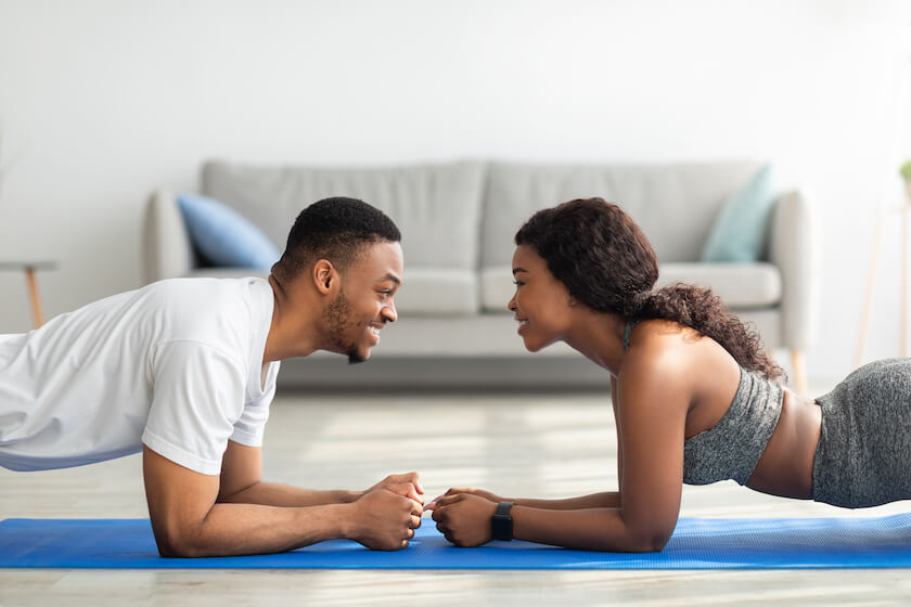 A couple face each as they perform the plank exercise feeling connected and aligned together.