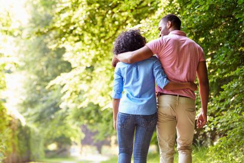 Couple walk arm in arm along a green leafy lane reflecting on the quiet moments that bring them closer.