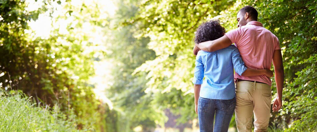 Couple walk arm in arm along a green leafy lane reflecting on the quiet moments that bring them closer.