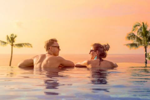 Couple look at each other in an infinity pool on honeymoon earning each other's hearts.