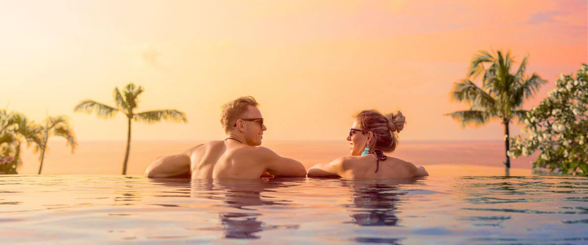 Couple look at each other in an infinity pool on honeymoon earning each other's hearts.