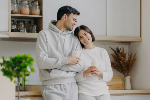 Newlywed couple standing having coffee after moving into their first home building a healthy start together.
