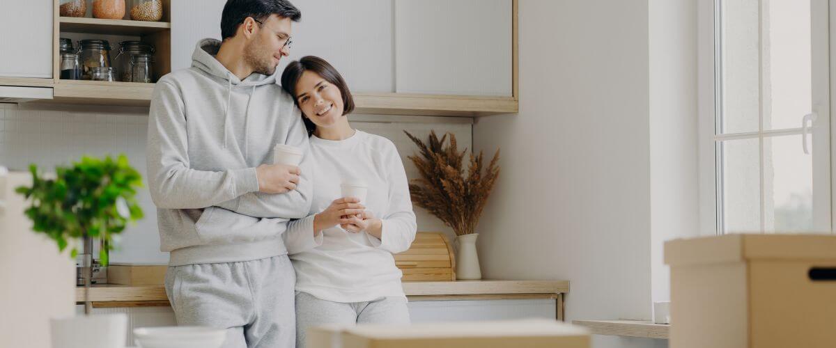 Newlywed couple standing having coffee after moving into their first home building a healthy start together.