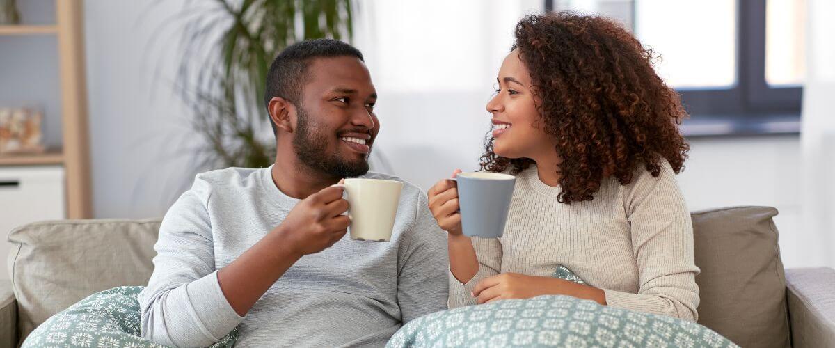 Couple sit on sofa talking having coffee forming the foundations of their relationship.