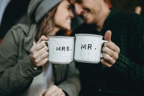 Newlywed couple sitting outside holding hugs with Mr and Mrs written on them navigating the first year as a team.