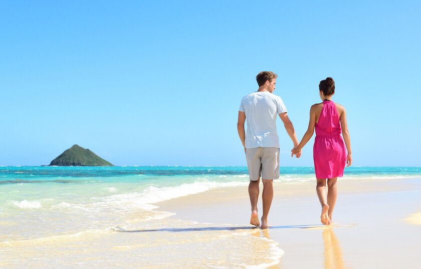 A newlywed couple, walk hand in hand along a beach, talking about their future, representing the foundational skills hub.