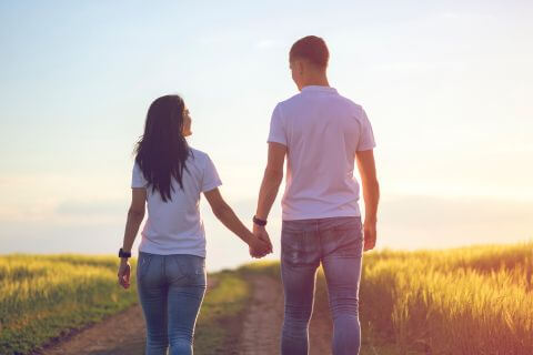 Couple walk hand in hand along a lane finding the balance between me and us.