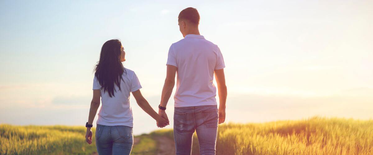 Couple walk hand in hand along a lane finding the balance between me and us.