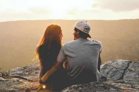 Couple sit at top of a mountain with the horizon in front of them, reflecting on the importance of self-awareness in marriage.