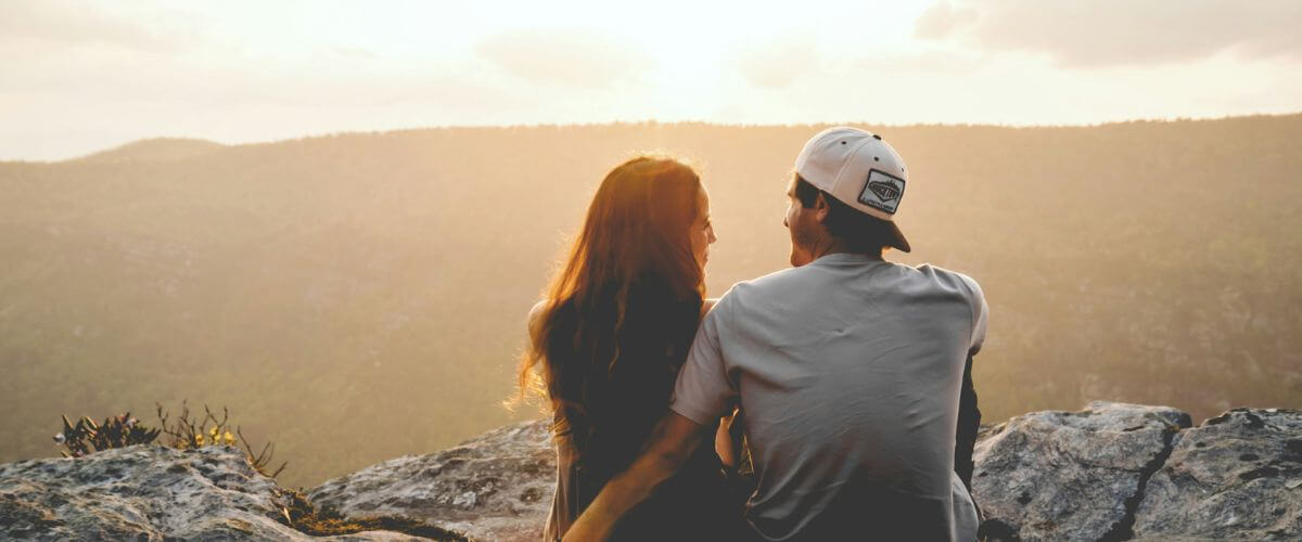 Couple sit at top of a mountain with the horizon in front of them, reflecting on the importance of self-awareness in marriage.