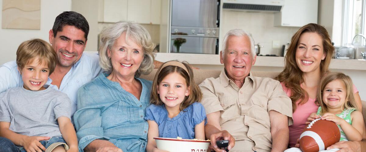 Multi-generational family sit on sofa representing impact of upbringing on relationships.