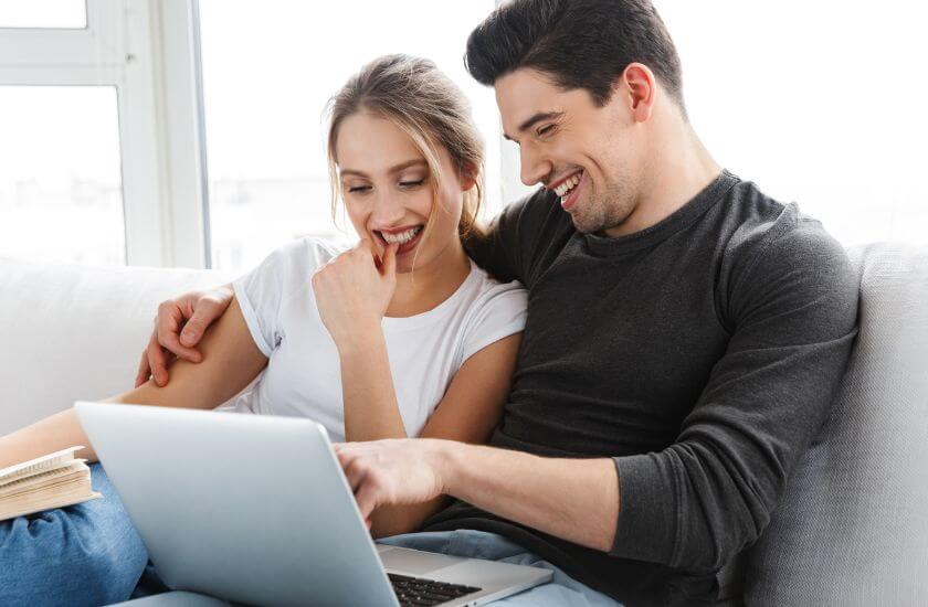 Newlywed couple look at a laptop completing the marriage foundations health check.
