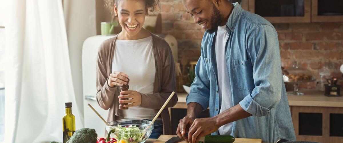 Couple prepare a salad together, discussing personal growth.