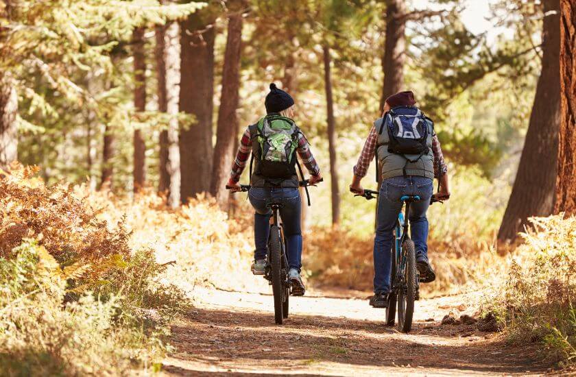 Couple ride bikes along a woodland track appreciating time together