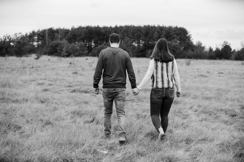 Couple walk hand in hand across a filled, reflecting on how to strengthen their bond