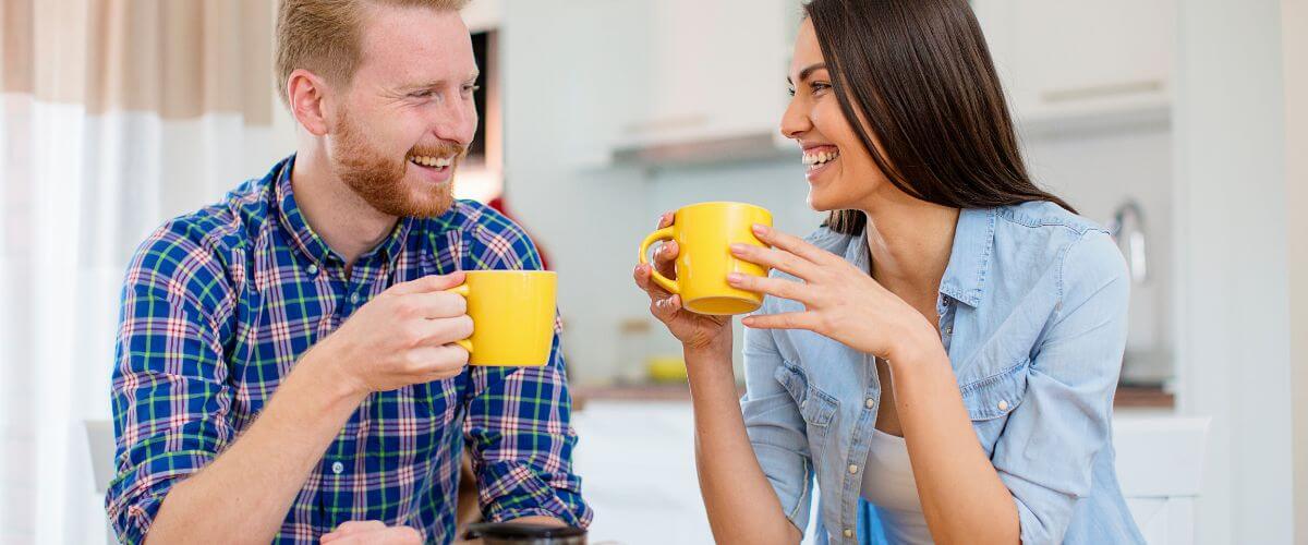 Couple talk while having coffee at the kitchen table having the little conversations that shape their future.